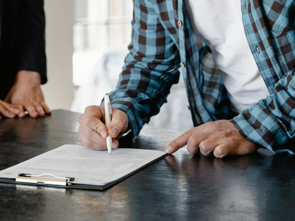 A closeup of a man signing a last will and testament provided for him by the Law Office of Don Johnson.